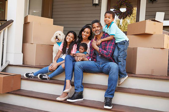Family sitting on steps of home with moving boxes